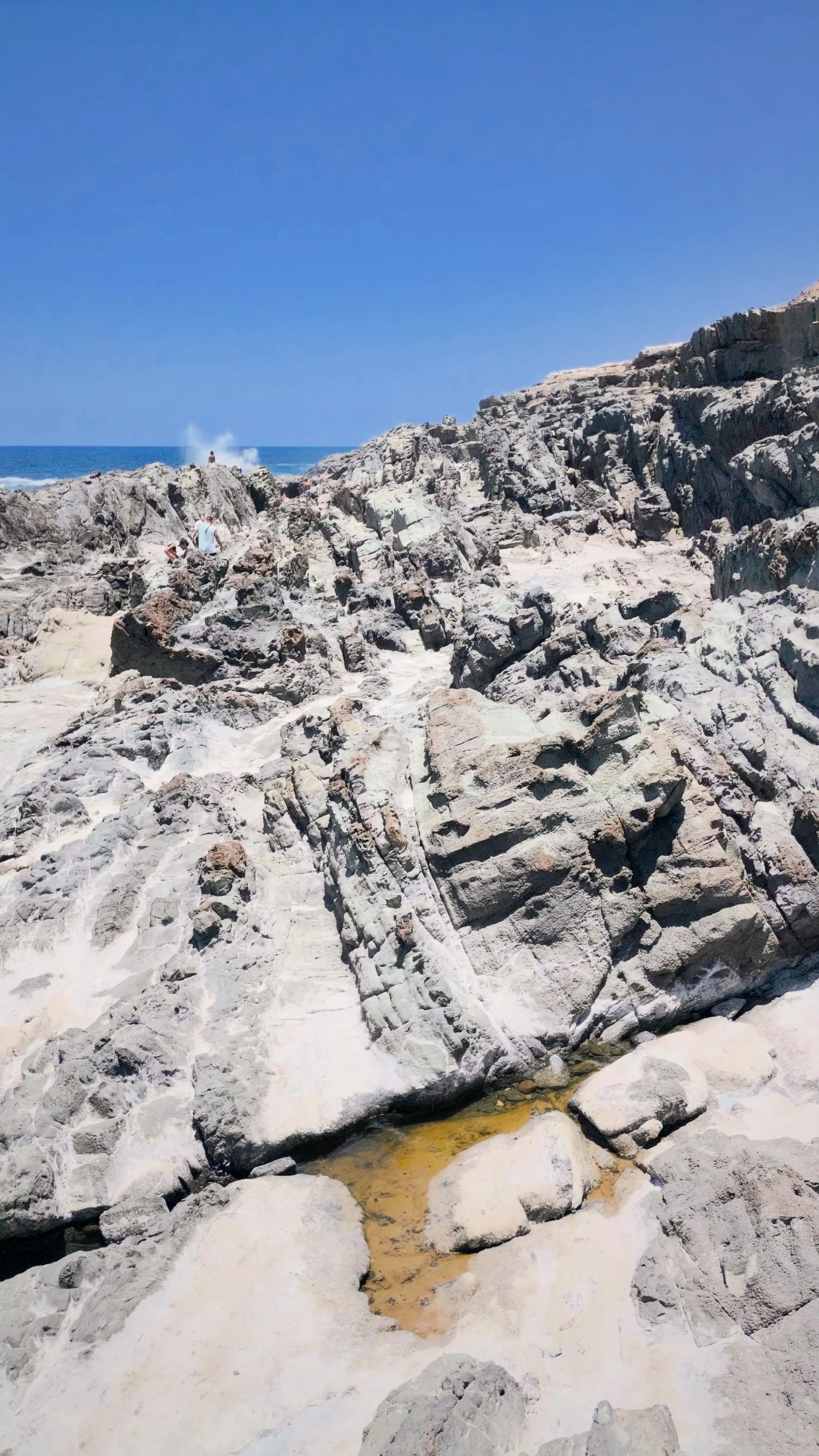 Strati di roccia sedimentaria sovrapposti su una parete costiera, ripresi da drone in verticale
