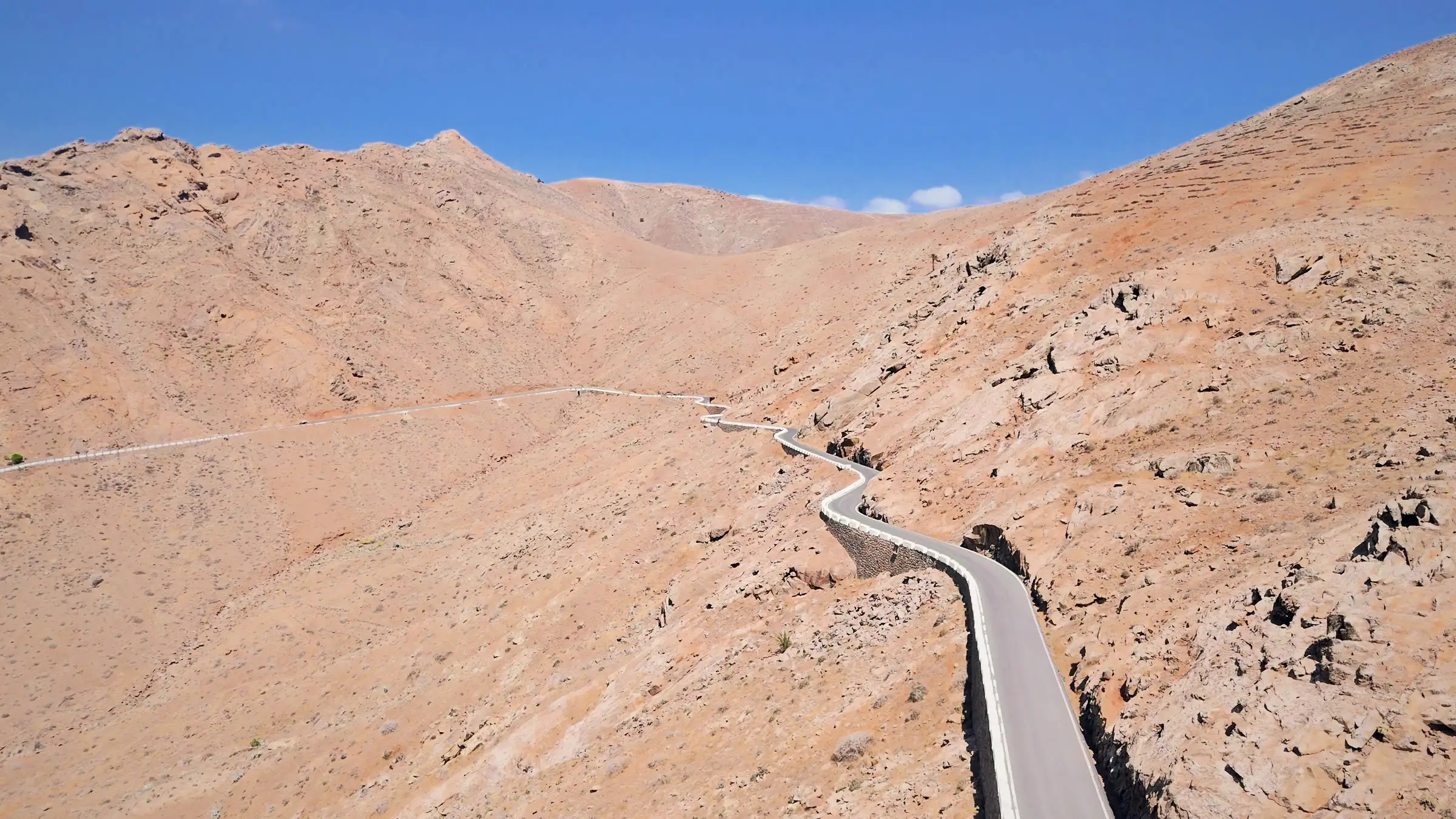 Strada a tornanti che attraversa le montagne vulcaniche di Fuerteventura, ripresa da drone