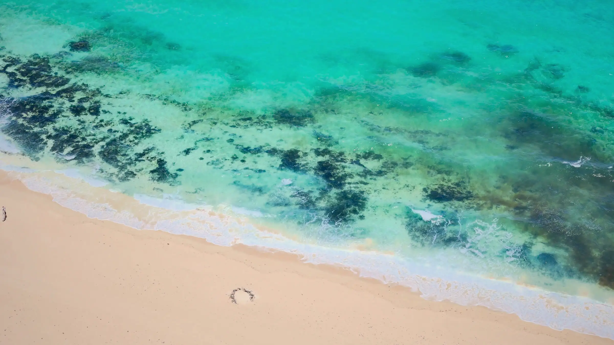 Spiaggia chiara e barriera corallina affiorante, visti dall'alto con il drone