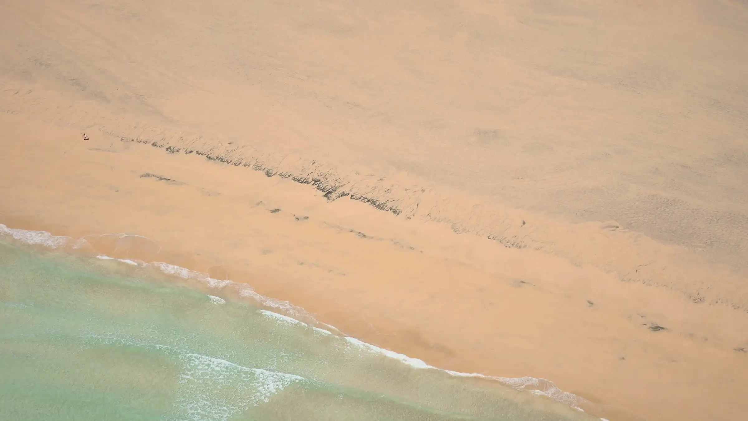Lingue di sabbia chiara che si allungano dentro l'acqua bassa di una laguna