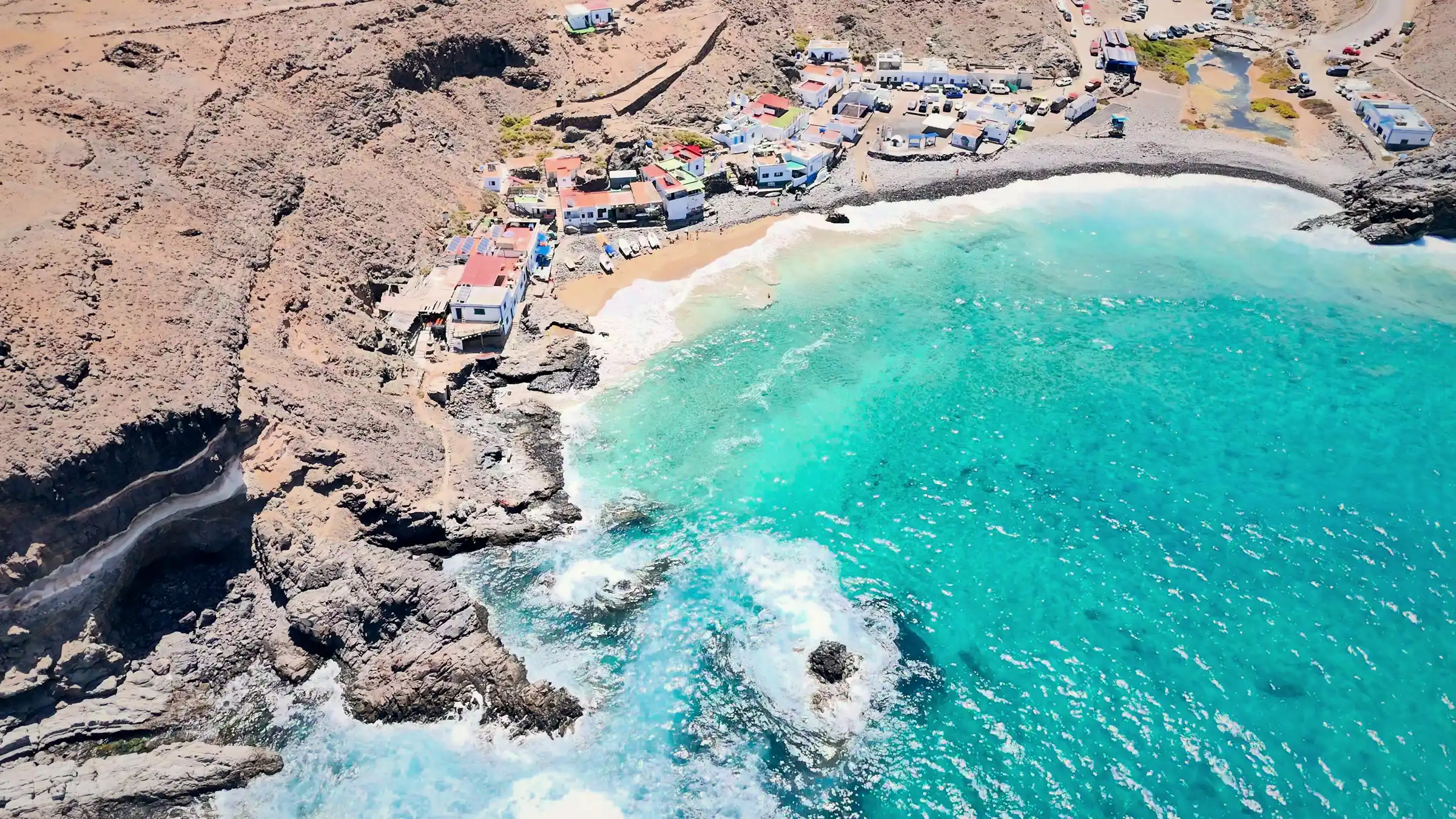 Baia dall'acqua turchese con il villaggio di Ajuy sulla costa ovest di Fuerteventura, ripresa da drone