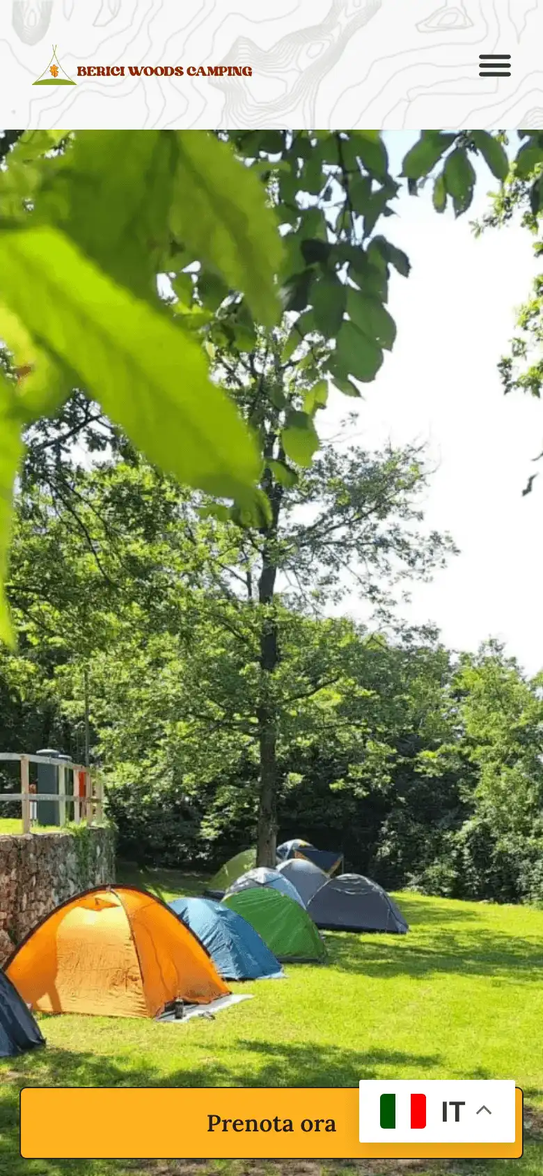 La home del campeggio sul telefono: il marchio, il menu e le tende sul prato, con il bottone per prenotare in basso.