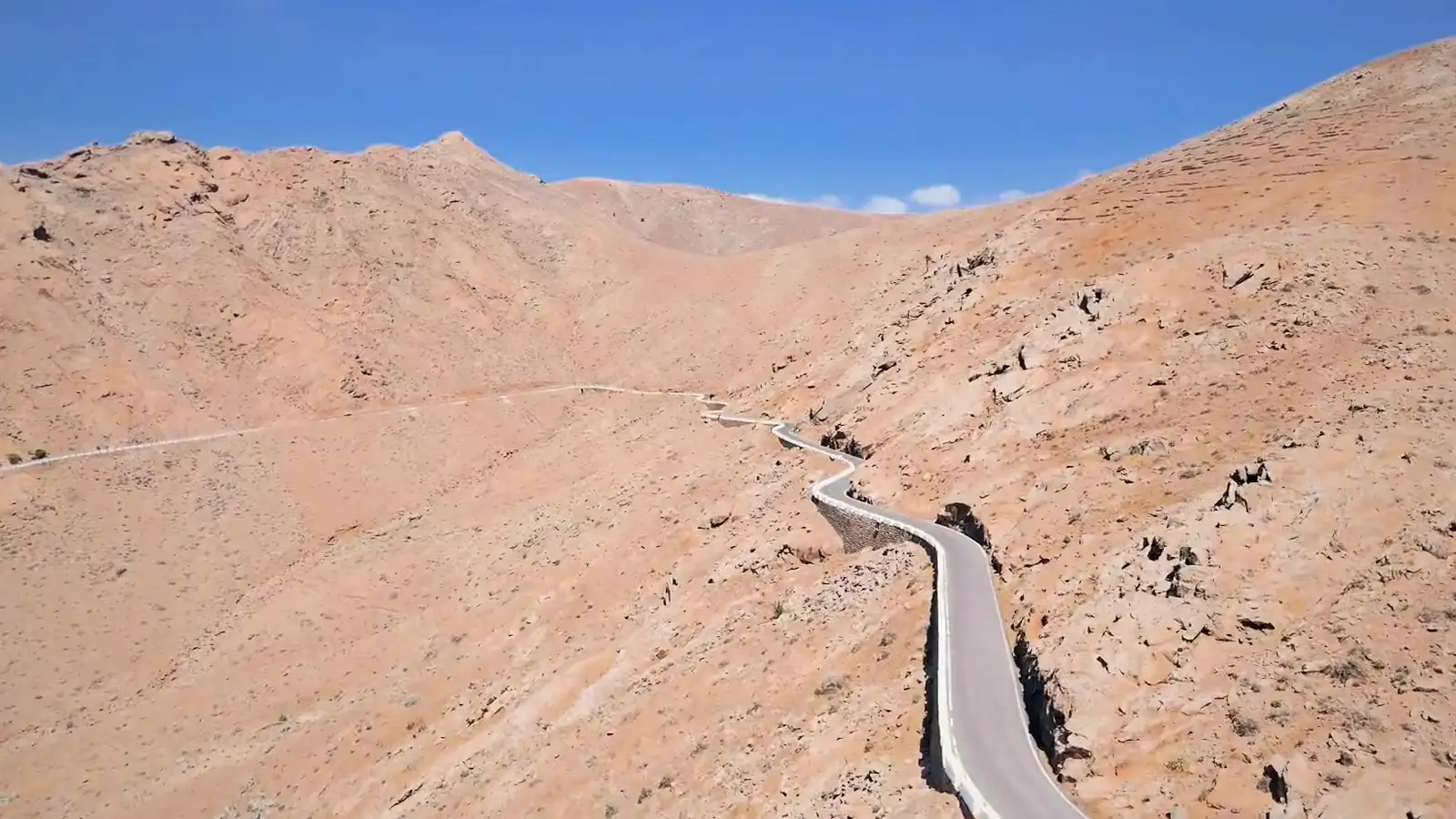 Strada a tornanti che attraversa le montagne vulcaniche di Fuerteventura, ripresa da drone