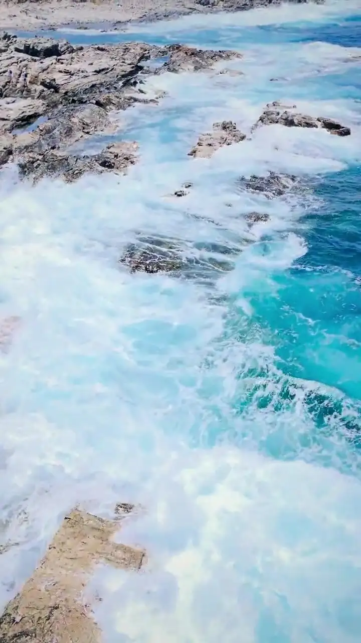 Loop verticale: onde che avanzano verso la costa e si aprono in schiuma bianca
