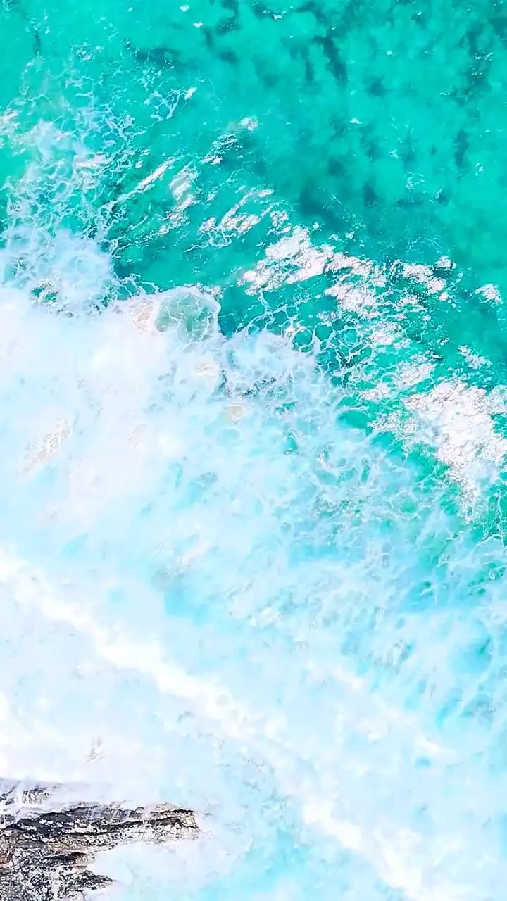 Montaggio verticale sull'oceano: costa rocciosa, onde e acqua aperta ripresi da drone